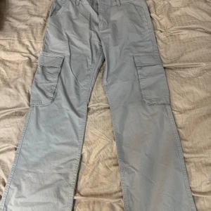 Grå cargobyxor - Säljer ett par grå cargobyxor i bra skick. De har flera praktiska fickor på sidorna och bak, perfekt för vardagsbruk eller äventyr. Byxorna har en loose passform och är tillverkade i ett slitstarkt material. Perfekta för höst och vår!