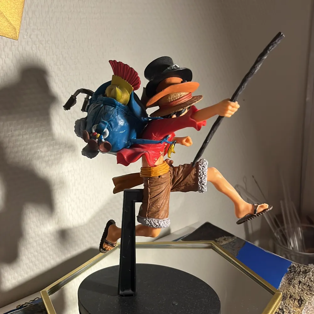 Monkey D. Luffy figur. Pinnen går att ta bort och sitter inte fast. Mycket fina detaljer från de olika arken. Även alla 3 brödernas hattar på. Figuren står på ett svart stativ och ser ut att vara i rörelse, vilket ger en dynamisk känsla. Perfekt för fans av äventyr och samlarobjekt!. Accessoarer.