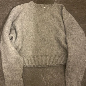 Grå stickad tröja - Mysig grå stickad tröja som är lite croppad. Perfekt för kyliga dagar med sin varma och bekväma passform. Tröjan har långa ärmar och ribbade kanter, passar till allt💕💕