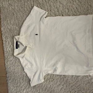 Vit kortärmad pikétröja från Ralph Lauren - Säljer en klassisk vit pikétröja från Ralph Lauren i storlek L. Tröjan är i bomull och har en broderad logga på bröstet. Den är i custom slim fit och passar perfekt för både vardag och fest. Skicket är mycket bra, nästan som ny!