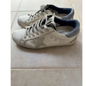 Golden Goose sneakers  - Säljer ett par vita Golden Goose sneakers med en cool stjärndetalj på sidan. De har en grå häl och snörning framtill. Perfekta för en avslappnad stil och passar till det mesta. Skriv för egna bilder eller andra frågor 💙💙