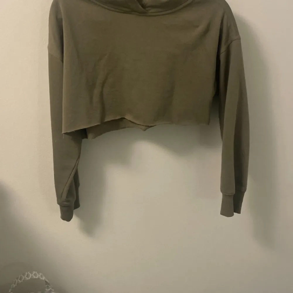 Säljer en olivgrön croppad hoodie i bra skick. Den har en avslappnad passform med långa ärmar och en mysig huva. Perfekt för en chill dag eller att slänga på sig efter träningen. Passar bra till både jeans och leggings! Den är avklippta med repar inte upp sig, nästan aldrig använd. Neuletakit & Villapaidat.