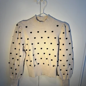 Vit stickad tröja med svarta prickar - Superfin vit stickad tröja med svarta prickar över hela. Den har långa ärmar och en ribbad krage som ger en mysig känsla. Perfekt för höst och vinter, och den är i mycket bra skick. Passar både till vardags och lite finare tillfällen.💕🥰