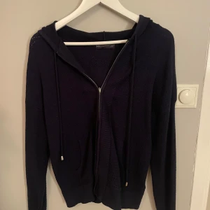Mörkblå hoodie från M&S Collection - Säljer en snygg mörkblå hoodie från M&S Collection i storlek S. Den har dragkedja och huva med snören, perfekt för kyliga dagar. Tröjan är i bra skick och passar både till vardags och mysiga hemmakvällar. Skön och stilren design!