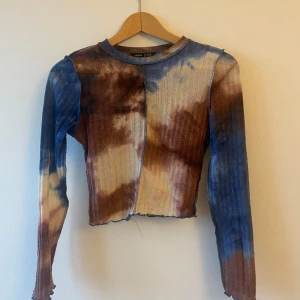 Flerfärgad ribbad tröja - Säljer en cool flerfärgad ribbad tröja med lång ärm. Den har ett unikt batikmönster i blått, brunt och beige.