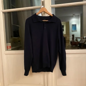 Mörkblå långärmad tröja från J.Crew - Säljer en stilren mörkblå tröja från J.Crew i storlek L. Tröjan är tillverkad av 50% merinoull och 50% akryl, vilket gör den både varm och bekväm. Perfekt för höst och vinter! Den har en klassisk krage och långa ärmar, vilket ger en tidlös look.