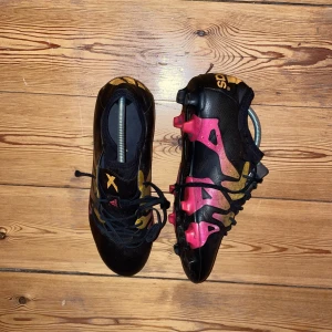 Fotbollsskor Elite (Adidas X) - Säljer ett par svarta Adidas fotbollsskor i bra skick. De har coola rosa och gula detaljer och snörning för perfekt passform. Perfekta för fotbollsträning eller match! ⚽