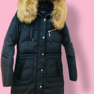 Svart dunjacka från Hollies - Säljer en snygg svart dunjacka från Hollies i storlek 34. Den har en fluffig äkta päls på huvan och guldiga dragkedjor och knappar. Perfekt för kalla vinterdagar! sparsamt använd eftersom den är lite för liten för mig, så den är i nästan ny skick. Ordinarie pris är 4300 kr. Jackan finns i Uppsala men kan också fraktas spårpart