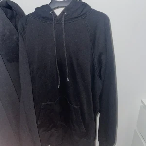 Svart hoodie från HM - Säljer en klassisk svart hoodie från HM. Den har en bekväm passform med långa ärmar och en praktisk magficka. Huvan har dragsko för justering. Perfekt för en avslappnad stil. Storlek xs men skulle säga att den lätt passar folk 170-175cm.