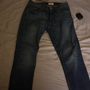 Mörkblå jeans från Tiger of Sweden - Snygga mörkblå jeans från Tiger of Sweden med klassisk femficksdesign och knappgylf. Perfekta för en stilren look. Jeansen har en rak passform och är tillverkade i slitstarkt denim.