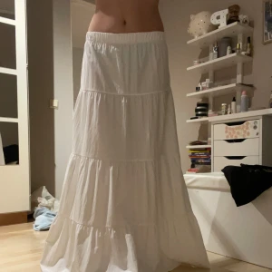 Vit långkjol - Säljer en vit långkjol med volanger. Kjolen har en luftig och bekväm passform, perfekt för varma dagar. Den elastiska midjan gör den passar många olika storlekar! Den är använd 2 gånger, har en till så denna har inte kommit mycket till användning!!!
