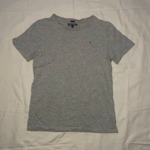 Grå t-shirt från Tommy Hilfiger - Säljer en stilren grå t-shirt från Tommy Hilfiger i ekologisk bomull. Den har en liten broderad logga på bröstet och är kortärmad. Perfekt för en avslappnad look.
