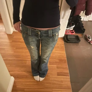 Blå jeans från true religion - Säljer ett par blå jeans från true religion  med bootcut-stil. De har en låg midja,  Perfekta för en avslappnad look. De är lite slitna där nere bak på jeansen (skriv för fler bilder)😊
