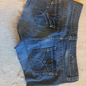 Blå jeansshorts från Calvin Klein - Snygga blå jeansshorts från Calvin Klein med fransiga kanter och klassiska femficksdesign. Perfekta för en avslappnad stil. De har en knapp och dragkedja framtill. Säljer pågrund av flytt och för mycket kläder😄😄