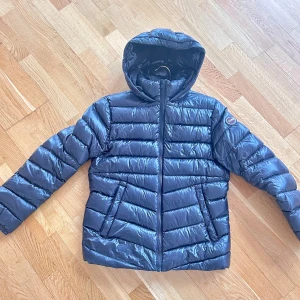 Nero Dark steel dunjacka från Colmar - Säljer en snygg svart dunjacka från Colmar. Jackan har en glansig finish och med en huva. 