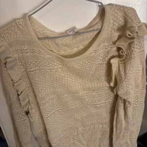 Beige stickad tröja från Stories - Säljer en beige stickad tröja från Stories med volangdetaljer på axlarna. 