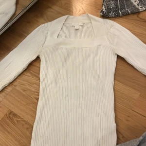 Vit ribbad tröja från H&M - Säljer en stilren vit ribbad tröja från H&M. Tröjan har långa ärmar och en fyrkantig halsringning som ger en elegant touch. Perfekt för att matcha med både jeans och kjol. Hör av dig vid intresse!
