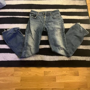 Blå jeans från Lee - Säljer ett par klassiska blå jeans från Lee. De har en snygg tvätt och är utrustade med knappar framtill. Perfekta för en avslappnad stil. Aldrig använda storlek 32 34