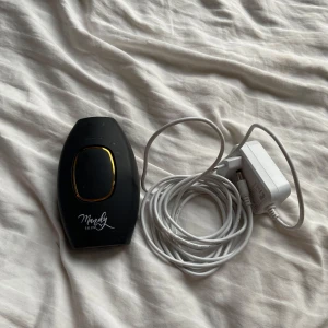 Svart IPL-enhet från Mandy Skin - Säljer en svart IPL-enhet från Mandy Skin med gulddetaljer. Perfekt för hårborttagning hemma. Enheten kommer med en vit strömkabel och adapter. Enkel att använda och smidig att förvara.