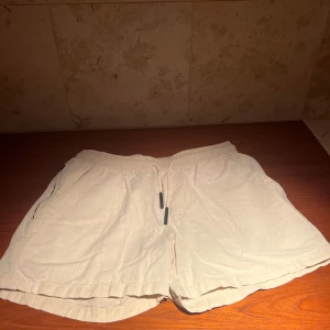 Beige linnéshorts från OAS - Snygga beige shorts från OAS i en skön linne- och bomullsblandning. De har en elastisk midja med snörning och praktiska fickor både fram och bak. Perfekta för varma dagar! Nya 1200kr och dessa är i nyskick. Riktigt kap!