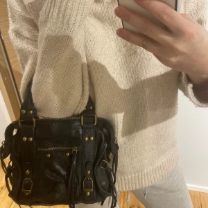 Svart axelväska med dragkedja - Snygg svart axelväska i skinn med flera dragkedjor och detaljer i metall. Väskan har både handtag och en justerbar axelrem för flexibel användning. Perfekt för att bära med sig det viktigaste med stil. Den är gjord av äkta leder och är köpt i Paris för en månad sen. Helt nytt skick. Fråga för fler bilder💕💕💕