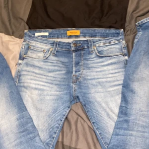 Blå jeans från Jack & Jones - Snygga blå jeans från Jack & Jones med en slim fit passform. De har en klassisk femficksdesign och en lätt tvättad look. Perfekta för en stilren vardagslook.(skriv om annat pris)