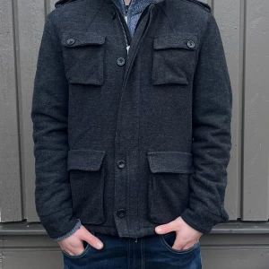 Stickad ull cardigan / vårjacka  - Riktigt stilig fodrad cardigan / jacka i ullblandning. Varm och skön, perfekt mot våren. Den har även luva som man kan ha av eller på. Knappar och dragkedja. Storlek 46 motsvarar cirka S. Modellen är ca 176. Fint skick. Skriv vid minsta intresse, pris kan diskuteras vid smidig affär 😀