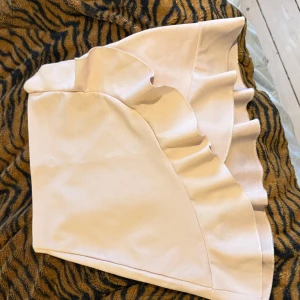 Beige kjol från NLY One - Säljer en söt beige kjol från NLY One i storlek XS. Kjolen har en volangdetalj som ger den en extra touch av stil. Perfekt för att piffa upp garderoben!