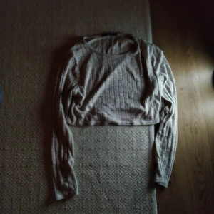 Beige ribbad croppad tröja - Säljer en beige ribbad croppad tröja med långa ärmar. Perfekt för en stilren och avslappnad look. Passar bra till både jeans och kjol. kontakta mig vid frågor om mer bilder, mått, pris osv🥰