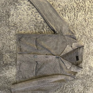 Grå cardigan från sand - Snygg grå cardigan från sand i bra skick förutom att den saknar en knapp