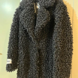 Svart teddyjacka från Jakke - Ny, fel storlek för mig… Säljer en mysig svart teddyjacka (fuskpäls) från Jakke. Jackan har en fluffig textur och är perfekt för kyliga dagar. Stilren med klassisk krage. Rätt liten i storleken.