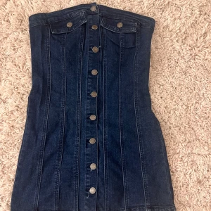 Bandeau jeansklänning - Säljer denna klänning jag köpte på en affär utomlands i somras, använd en gång och jag säljer då den är för stor på mig. Helt nytt och fint skick. Oklar storlek, runt S/M.