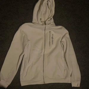 Vit hoodie från Sail Racing - Snygg vit kofta med dragkedja använd mycket. Dragkedjan på brösten är sönder går säkert att laga annars är den bra
