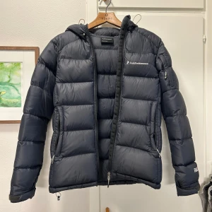 Svart dunjacka från Peak Performance - Snygg och varm svart dunjacka från Peak Performance. Skimrar i blått. Säljer för att den är för liten på mig. Använd men väl omhändertagen så inga synliga defekter.