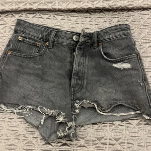 Grå jeansshorts med slitningar - Säljer ett par grå jeansshorts med slitningar och fransiga kanter. De har en klassisk femficksdesign och knappgylf. Perfekta för  sommaren💗💗säljer dessa då de inte passar mig längre. De är i storlek 34 från Zara❤️