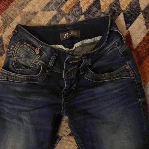 Mörkblå jeans från LTB - Snygga mörkblå jeans från LTB med klassisk femficksdesign och knappgylf. Priset kan diskuteras. Jeansen har en straight passform och är perfekta för en avslappnad stil. De har även dekorativa sömmar på bakfickorna. En liten slitning på framsida lår men det syns knappt och är snyggt. 