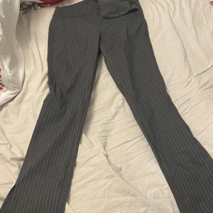 Grå randiga kostymbyxor - Snygga grå kostymbyxor från med diskreta ränder från New yorker . Perfekta för en stilren look. Byxorna har en normal passform och är tillverkade i ett bekvämt material. Oanvända