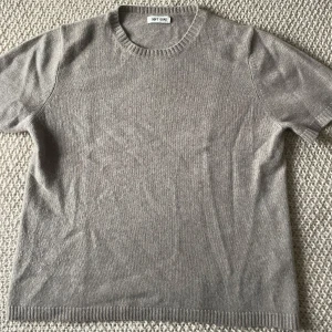  cashmere t-shirt från Soft Goat - Säljer en greige stickad t-shirt från Soft Goat. Den har korta ärmar och en rund halsringning. I cashmere och enbart använd en gång! 