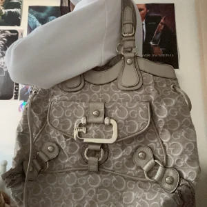 Beige axelväska Guess - Snygg beige axelväska från Guess med monogrammönster och stiliga metalldetaljer. Jag köpte den på Vinted för ett år sen men endast använt en gång 💕