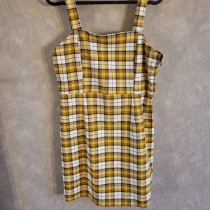Gul och vit rutig klänning från H&M Divided - Snygg gul och vit rutig klänning från H&M Divided med breda axelband. Perfekt för en trendig look med sin klassiska rutiga design.