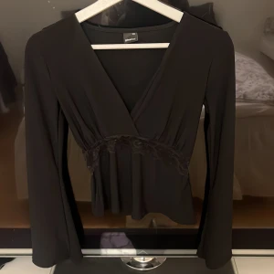 Svart omlottopp från Gina Tricot - Svart omlottopp från Gina Tricot. Toppen har en fin spetsdetalj under bysten. Använd endast en gång, fint skick. 