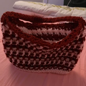 Handgjord stickad väska i rött och rosa - Charmig handgjord stickad väska i rött och rosa med ett unikt mönster. Perfekt för att ge en färgklick till din outfit. Väskan har en praktisk storlek och ett bekvämt handtag.