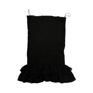 Svart topp med volangdetalj - Trendig svart topp  med volangdetalj i nederkant. Axelbandslös design som ger en stilren look. Perfekt för en kväll ute eller en speciell tillställning.