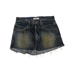 Jeanskjol med fransig kant - Snygg jeanskjol med en fransig kant och klassisk femficksdesign. Kjolen har en knapp och dragkedja framtill och är perfekt för en avslappnad stil.