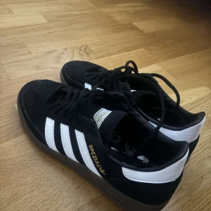 Svarta Adidas Spezial sneakers - Snygga svarta Adidas Spezial sneakers med vita ränder och detaljer. Skorna har en klassisk design med snörning och är perfekta för en avslappnad stil. De är tillverkade i mocka och har en bekväm passform.