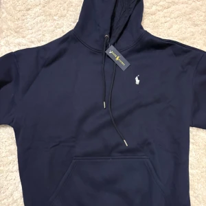 Mörkblå Polo Ralph Lauren hoodie - Helt ny Mörkblå Polo Ralph Lauren hoodie med taggen kvar. Säljer pga present som ej passade. Perfekt som julklapp!!