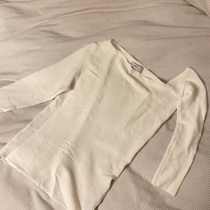 Vit ribbad tröja från Zara - Säljer en stilren vit ribbad tröja från Zara. Tröjan har en offshoulder-design och långa ärmar