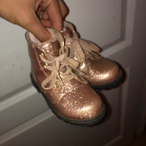 Glittriga rosa boots för barn - Säljer ett par glittriga rosa boots för barn med snörning. De har en robust sula och är perfekta för att lysa upp vilken outfit som helst. Storlek 23