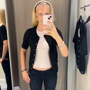 Svart kofta med knappar i nyskick🌟🩷 - Säljer en stilren svart kofta med knappar framtill. Perfekt för lager-på-lager och passar till många olika outfits. Koftan har korta ärmar och en klassisk design.