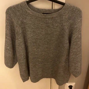 Grå stickad tröja från lager 157 - Mysig grå stickad tröja från lager 157 med trekvartsärm. Perfekt för kyliga dagar och enkel att matcha med jeans eller kjol. Tröjan har en rund halsringning och en avslappnad passform.